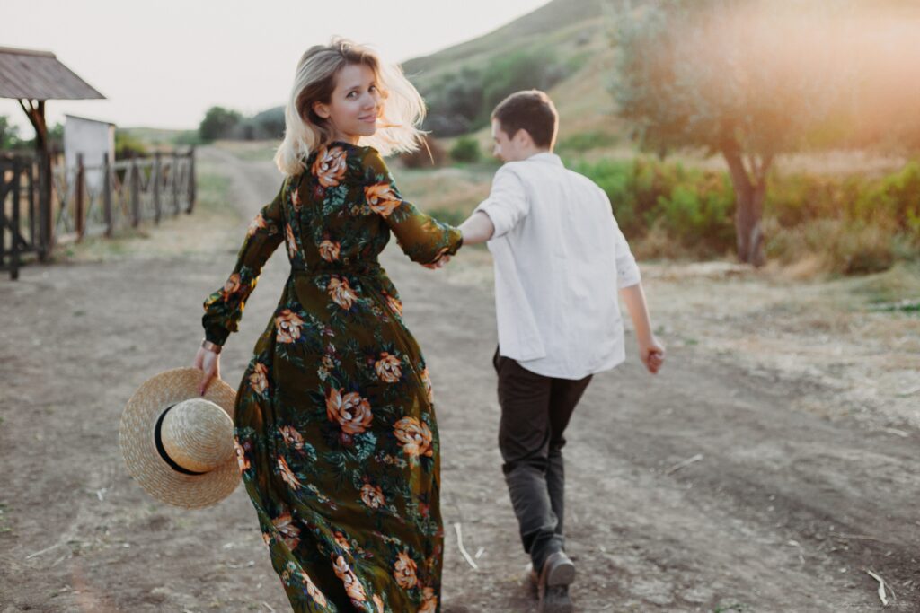 Man and a woman holdings hands appearing to be running wearing summer soiree attire