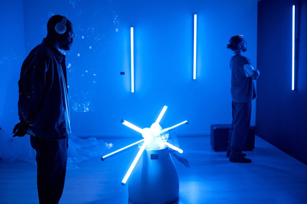 Attendees enjoying a futuristic art installation in a dark room illuminated by neon lights