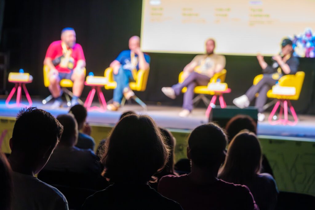 speakers sitting on a conference stage addressing the audience