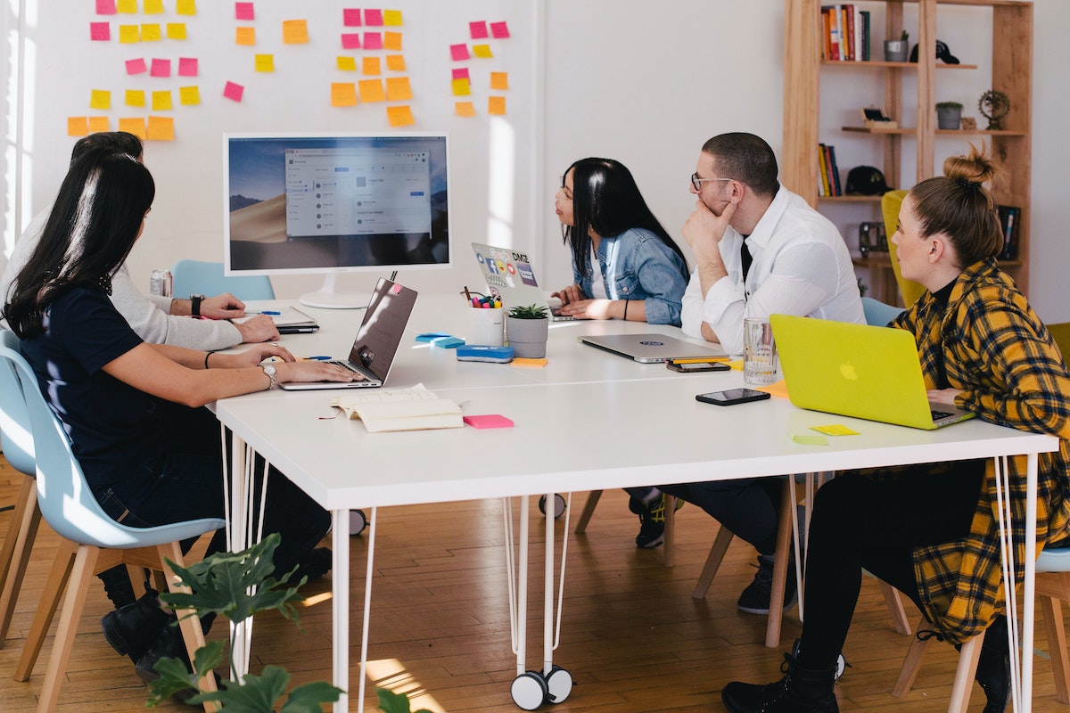 A team of four employees sit around a table during an event debrief meeting.