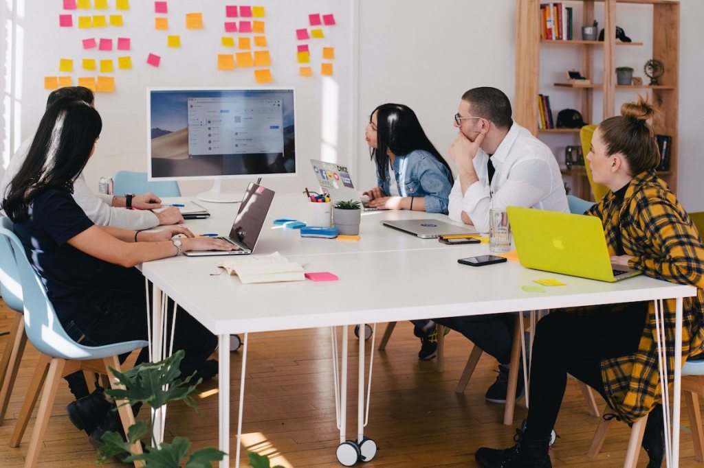 A team of four employees sit around a table during an event debrief meeting.