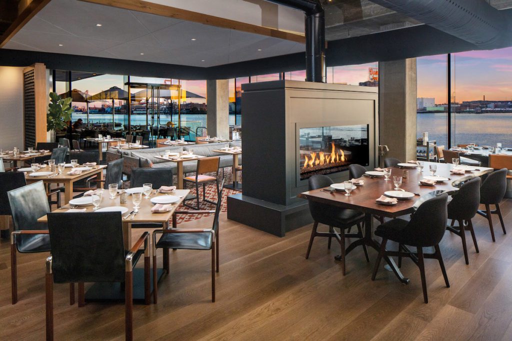 A dining room in the Hilton Canopy Harbor Point hotel with floor-to-ceiling views of Baltimore's harborfront.