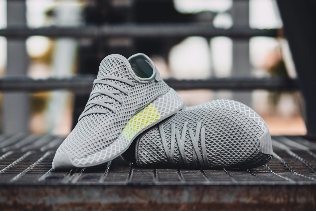 Pair of new grey sneakers laying outside on a metal staircase