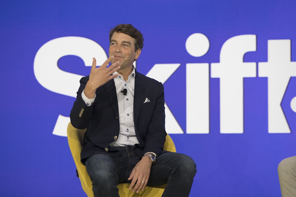 Man in a business suit sitting on stage at a conference