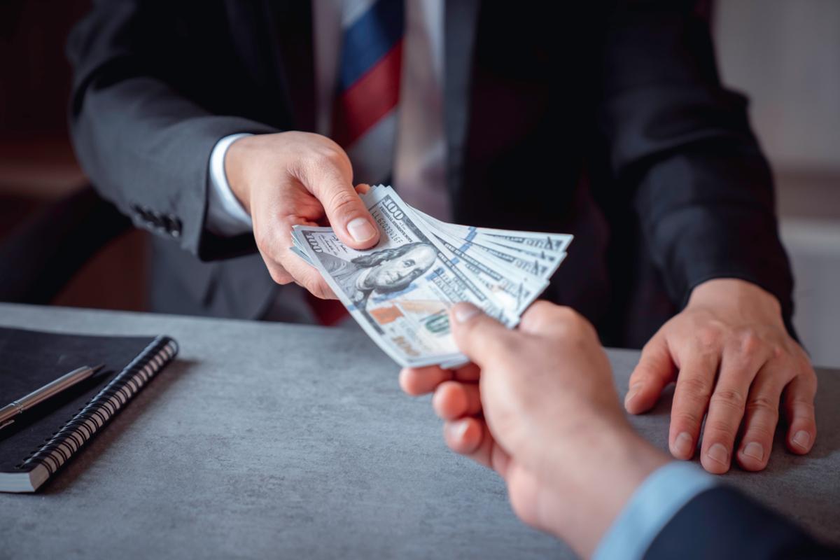 Businesspeople handing cash to each other for a cancellation.