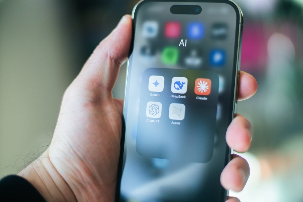 Man holding iPhone with AI apps on the screen